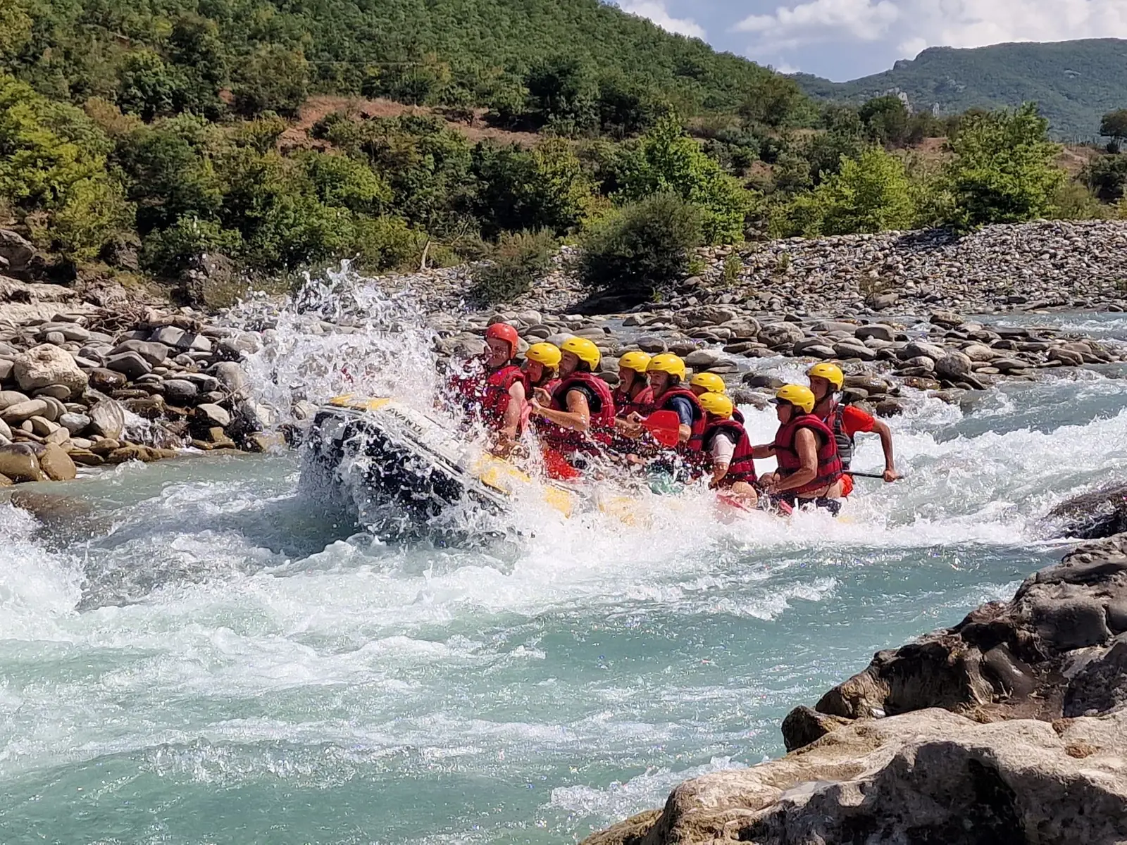 Groupe de rafting en casques et gilets affrontant une vague sur la Vjosa